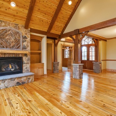 This gorgeous family room with its vaulted ceilings and stone fireplace is sure to create conversion. The Reclaimed Heart Pine Flooring will last generations. Notice the Hand Hewn Heart Pine Mantel above the fireplace. You can imagine sitting on the hearth warming up in the winter. - E.T. Moore Custom Home